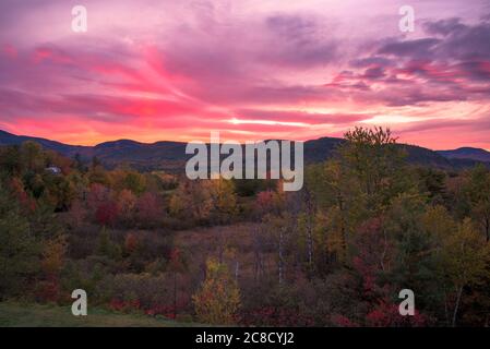 Stunning sunset over forested mountains at the peak of fall foliage Stock Photo