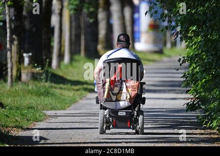 Munich, Deutschland. 23rd July, 2020. A disabled man who cannot walk is driving alone on his sidewalk on his scooter without an escort. | usage worldwide Credit: dpa/Alamy Live News Stock Photo