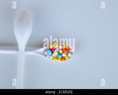 Multi colored sweet fennel sugar candy in white spoons against white background with copy space, isolated Stock Photo
