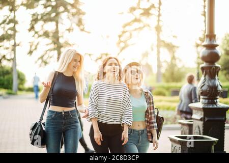 Three cute hippie girl sitting outdoors, best friends having fun and laughing Stock Photo