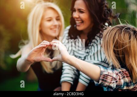 Adult sisters in a park at wonderful day making heart gesture Stock Photo