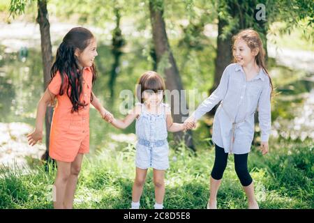 three kid sister friends girls group playing together in park Stock Photo