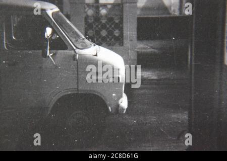 Fine 70s vintage black and white lifestyle photography of a white van driving by on the street. Stock Photo
