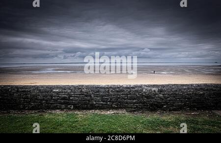 An Old Stone Wall In Front of a Cloudy Beach Scene Stock Photo