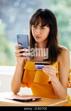 Woman looking at her phone and credit card Stock Photo