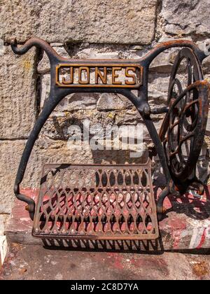 Remains of Antique Jones Treadle Sewing Machine against stone wall Stock Photo