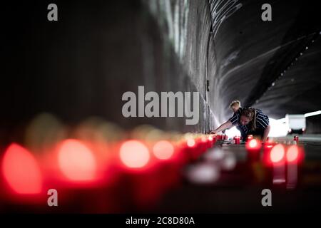 Duisburg, Germany. 23rd July, 2020. A woman lights a row of candles in the tunnel. Before the 10th anniversary of the mass panic at the Love Parade, in which 21 people die, the 'Night of 1000 Lights' takes place. In silent remembrance of the victims of the Love Parade disaster, people light candles at the memorial and the tunnel on Karl-Lehr-Strasse on the eve of the anniversary. Credit: Fabian Strauch/dpa/Alamy Live News Stock Photo