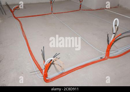Insulated electric cables are installed on the floor in a building under construction. Electrical cabling Stock Photo