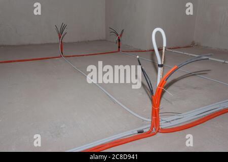 Insulated electric cables are installed on the floor in a building under construction. Electrical cabling Stock Photo