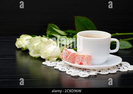 Coffee with milk, Turkish Delight bouquet of white roses on a black background Stock Photo