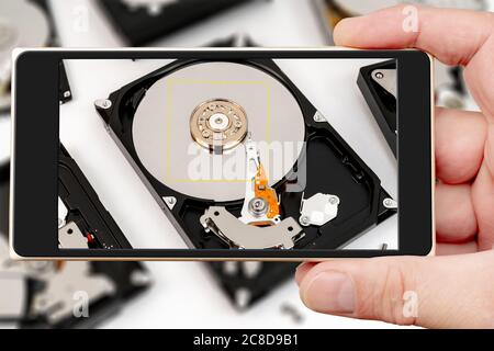 Computer hard drive on smartphone screen. Repair of electronic devices. Data store. Stock Photo