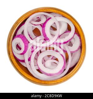Red onion rings in wooden bowl. Slices of the onion cultivar Allium cepa with purplish red skin and white flesh tinged with red. Closeup. Stock Photo