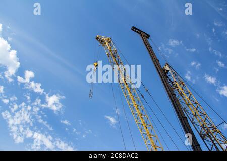 Tower crane and Bore pile rig machine at the construction site in Construction machinery against a blue sky with clouds Stock Photo