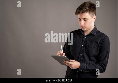 Portrait of serious stylish attractive man dressed with a casual black shirt taking notes isolated on gray background with copy space advertising area Stock Photo