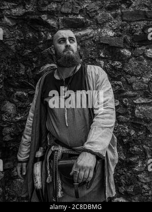 Viking warrior portrait with thick beard in front of a stone wall, black and white historical reenactment image Stock Photo