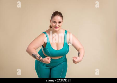 Pretty oversize woman wearing sportswear posing in studio - Beautiful girl accepting body imperfection, beauty shots in studio - Concepts about body a