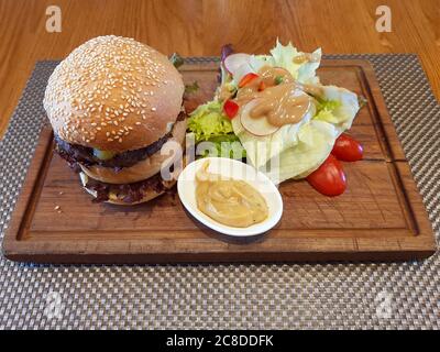 Double Cheeseburger Served On Wooden Plate At Restaurant Stock Photo