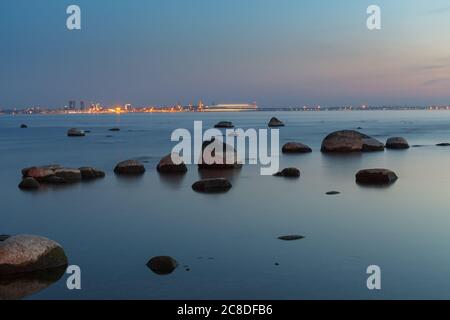 View of a rocky coast after sunset. Long exposure shot. Tallinn old town at the background. Stock Photo