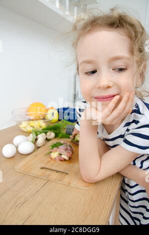 Portrait of funny cute little girl in the kitchen. Stock Photo