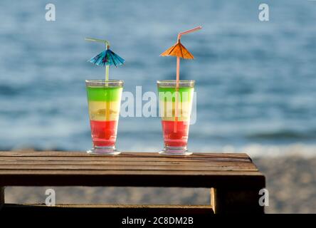 Multi-colored cocktails on a wooden table in the background on the beach and sea Stock Photo