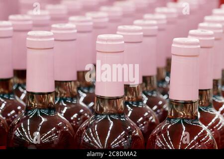 Wine bottles in a row, selective focus. Liquor store, pink wine production concept Stock Photo