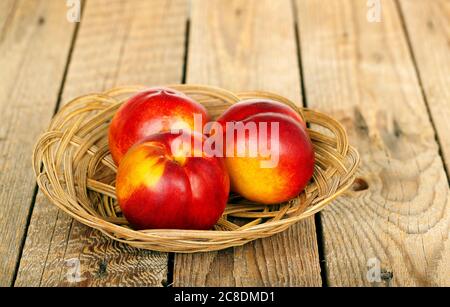 basket with nectarines on wooden surface Stock Photo