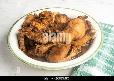 A serving of Filipino-style chicken adobo dish in a bowl with a green napkin set on a marble tabletop. Stock Photo