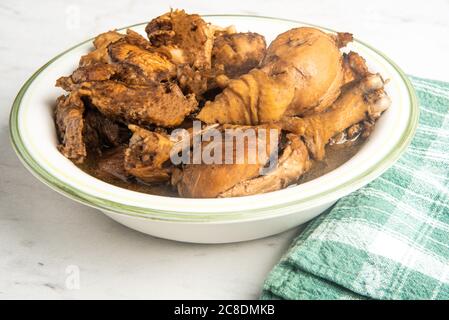 A serving of Filipino-style chicken adobo dish in a bowl with a green napkin set on a marble tabletop. Stock Photo