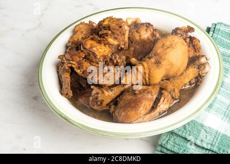 A serving of Filipino-style chicken adobo dish in a bowl with a green napkin set on a marble tabletop. Stock Photo