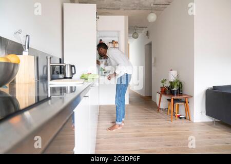 Man standing in the kitchen searching something in the fridge