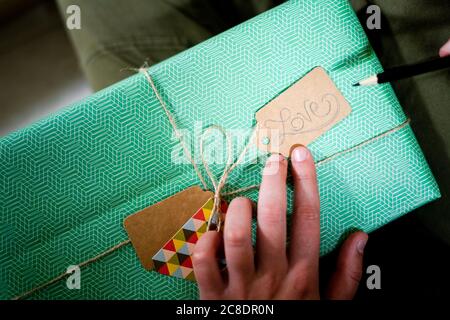 Hand holding tag with the word 'Love' on wrapped gift Stock Photo