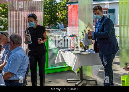 Outside catering with artistically designed partition walls and waiters with protective masks in Hotel Krone in Weil am Rhein, Germany. Service with mouth guard between distance objects by Samuel Treidl