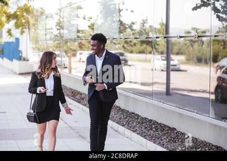 Business professionals discussing while walking on sidewalk in city Stock Photo