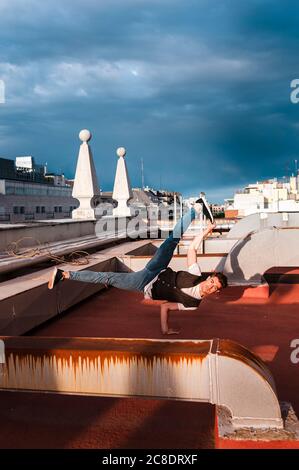 Confident young man breakdancing on abandoned building terrace against cloudy sky Stock Photo