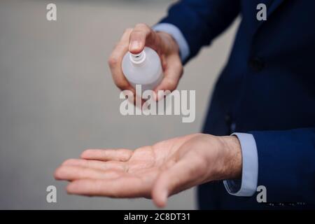 Close-up of businessman disinfecting his hands with a spray Stock Photo