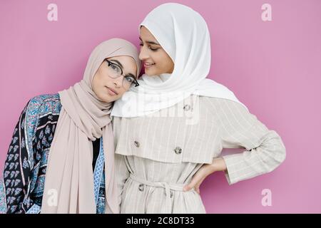 Muslim sisters standing against purple background Stock Photo