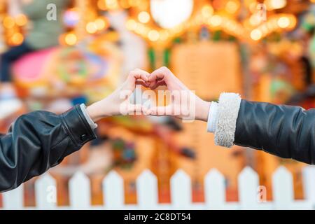 Close-up of couple hands making heart shape at amusement park Stock Photo