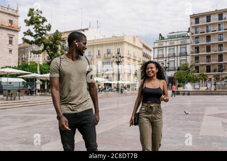 Happy man and woman walking on city street Stock Photo