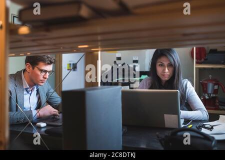 Businessman and woman using laptop at desk in office Stock Photo