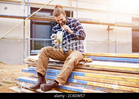 Happy worker having lunch break on a construction site Stock Photo