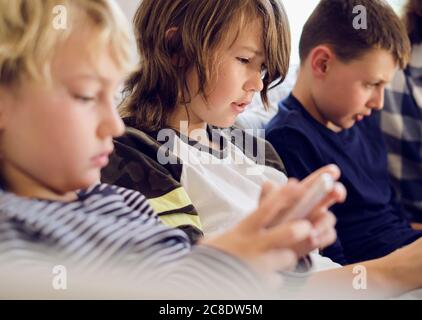 Boy playing games on smart phone with family in background at living room Stock Photo