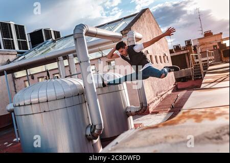 Male dancer jumping on abandoned building terrace against sky Stock Photo