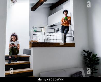 Two young women using their smartphones at home Stock Photo
