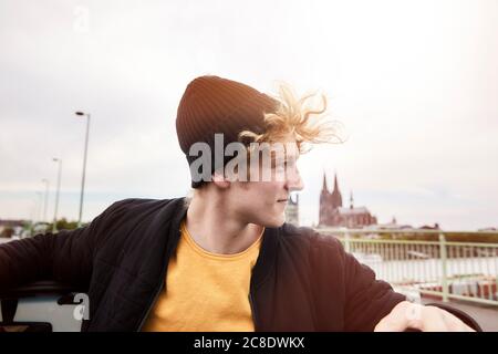 Portrait of young man with blowing hair wearing black cap, Cologne, Germany Stock Photo