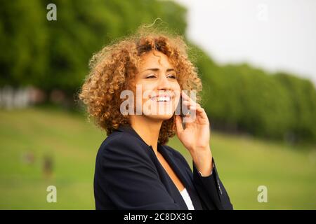 Close-up of smiling businesswoman talking over smart pone while standing outdoors Stock Photo