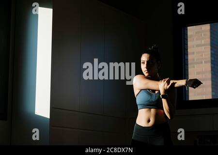 Young woman stretching her arm at home Stock Photo