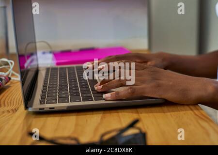 Cropped hands of young woman using laptop on table while studying at home Stock Photo