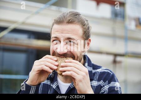 Portrait of worker having lunch break on a construction site eating a bread Stock Photo