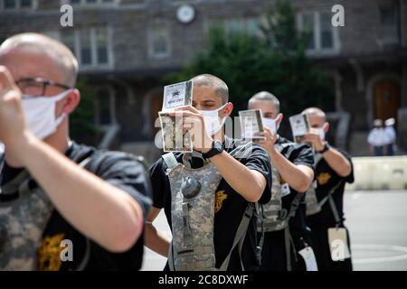 West Point cadets, social distance while studying the New Cadet Handbook after arriving at the U.S. Military Academy July 13, 2020, in West Point, New York. The class of 2024 is more than 1,200 strong and were required to be tested for COVID-19 upon arrival, wear masks, and practice social distancing. Stock Photo