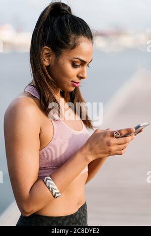 Close-up of female athlete using smart phone while standing at harbor Stock Photo